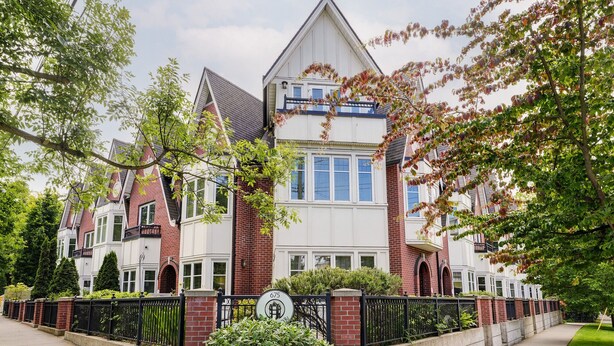 A Victorian-style house with a prominent front porch, a brick facade, and a large front yard.
