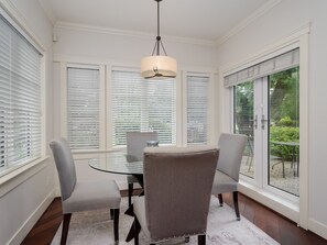 Uma área de refeições com mesa de vidro, quatro cadeiras e um lustre.
