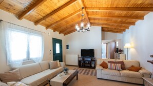 A living room with a wooden ceiling, two sofas, a coffee table, and a television. -  Villa Pine Forest  (Corfu)