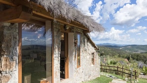 Un edificio de piedra con techo de paja y ventanas amplias.