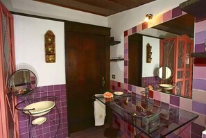 A bathroom with a glass sink, two mirrors, and a decorative wall panel. - Casa Conti di Sotto (Gavorrano)