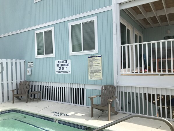 A pool area with a lifeguard warning sign, a pool rules sign, and two Adirondack chairs. - Coral Surf B-1 - 2 Bedroom, 2 Full Bath Oceanfront First floor Center Unit (Carolina Beach)