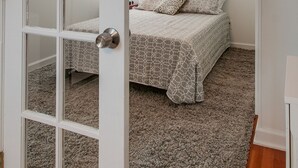 Un dormitorio con cama, piso alfombrado y lámpara de techo.