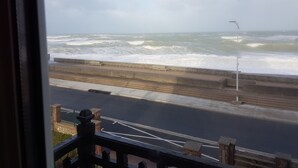 A view of the sea from a window, with waves crashing onto the shore. - "FACING THE SEA" VEULETTES SUR MER APARTMENT (Veulettes-sur-Mer)