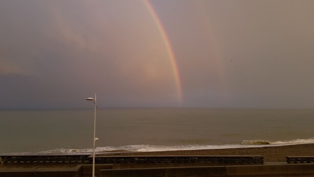 A beach with a rainbow, a street lamp, and a view of the ocean. - "FACING THE SEA" VEULETTES SUR MER APARTMENT (Veulettes-sur-Mer)