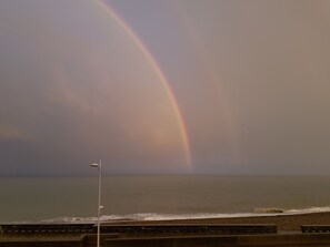 A beach with a rainbow, a street lamp, and a view of the ocean. - "FACING THE SEA" VEULETTES SUR MER APARTMENT (Veulettes-sur-Mer)