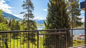 Ein Balkon mit Blick auf einen See, umgeben von Bäumen und Bergen.