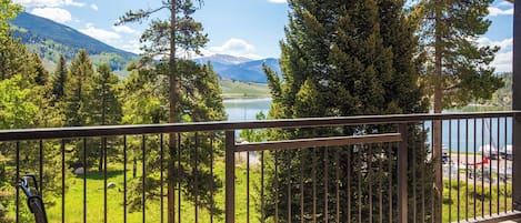A balcony with a view of a lake, surrounded by trees and mountains.