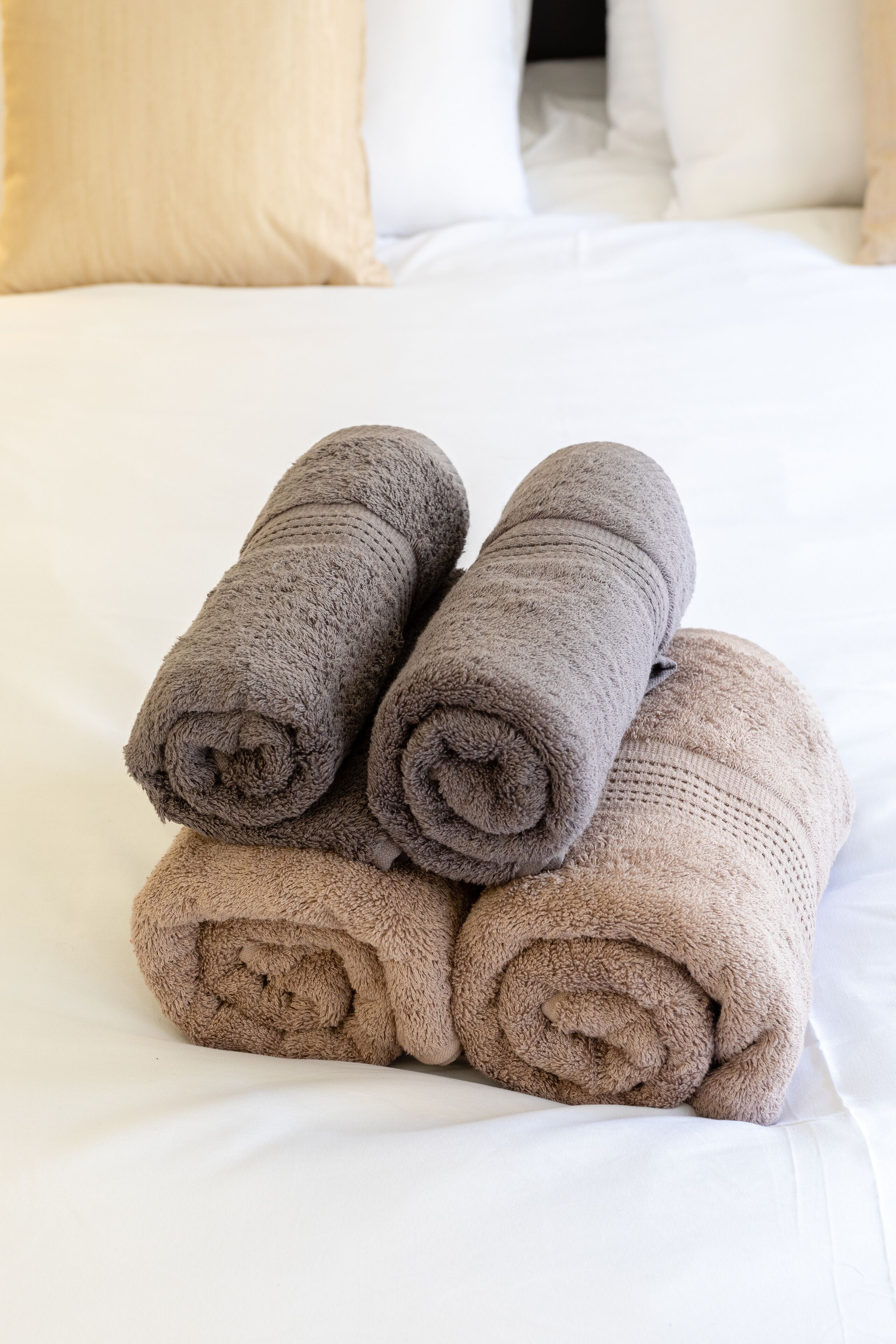 Una cama con toallas enrolladas con cuidado en tonos marrones y beige.
