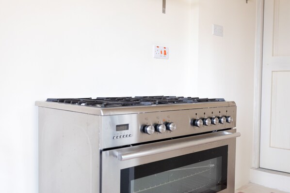 Una cucina con piano cottura e forno in acciaio inox, una parete bianca e una porta.