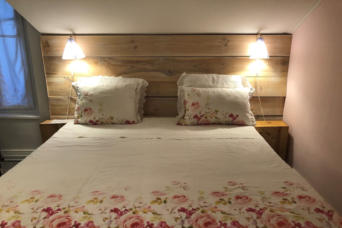 A bed with floral bedding, two bedside lamps, and a wooden headboard.