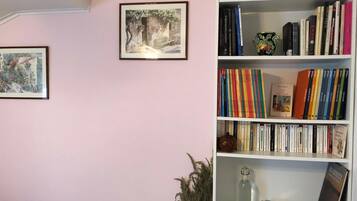 A room with a bookshelf filled with books, a framed picture on the wall, and a small decorative item on the shelf.