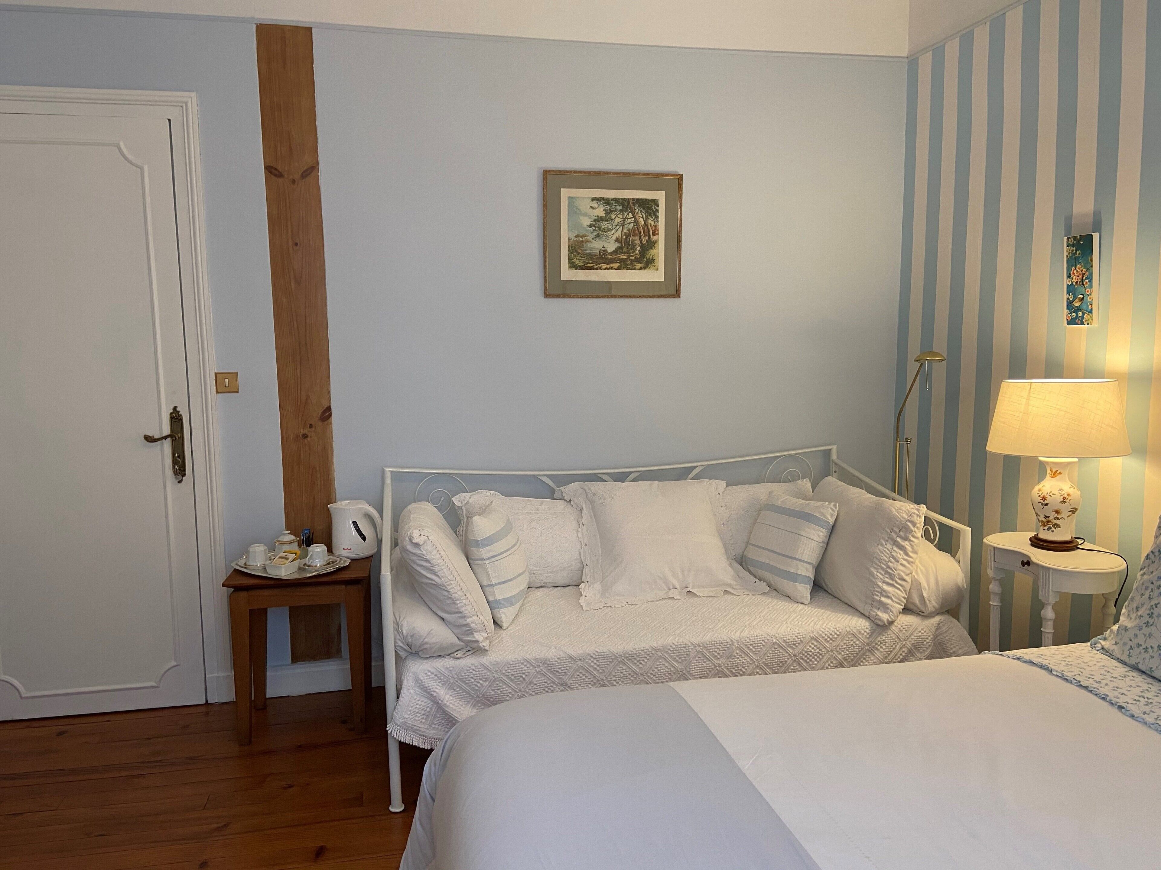A bedroom with a bed, bedside table, lamp, and a painting on the wall.