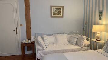 A bedroom with a bed, bedside table, lamp, and a painting on the wall.