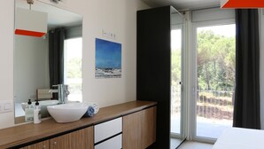 Une salle de bain moderne avec un grand miroir, un lavabo blanc et un meuble-lavabo en bois.
