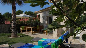 A patio with outdoor furniture, a stone wall, and a palm tree. - Villa Vuelta , spacious house with private pool (Pals)