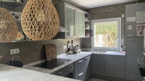 A modern kitchen with grey cabinets, a stainless steel sink, and a window with a view of greenery. - Villa Vuelta , spacious house with private pool (Pals)