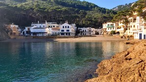 Eine Küstenstadt mit Gebäuden entlang der Uferlinie, freier Meeresblick und ein felsiger Strandabschnitt.