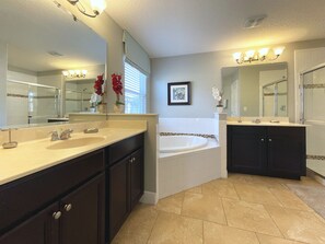 A modern bathroom with two sinks, a bathtub, and a large mirror.
