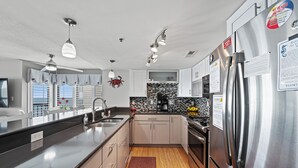 A modern kitchen with stainless steel appliances, a large island, and pendant lighting. - Updated!!! Crescent Towers II 708,  2 BR Ocean Front Luxury Condo with Pool (North Myrtle Beach)
