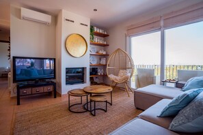 Un salon avec un téléviseur, un canapé et un balcon offrant une vue agréable.