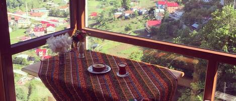 Un balcon avec une table dressée pour deux personnes, donnant sur un village.