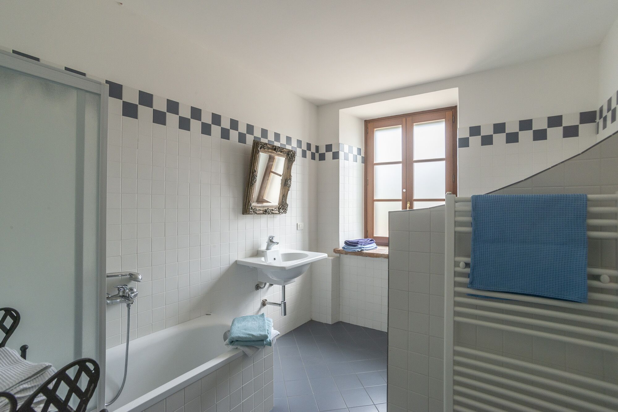 Ein Badezimmer mit Badewanne, Waschbecken, Spiegel und Fenster.