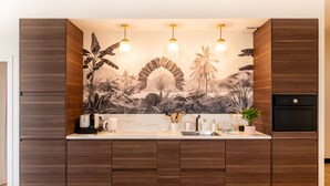 Una cocina con gabinetes de madera, encimera de mármol y un mural tropical.