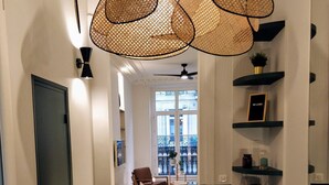 Un pasillo con alfombra estampada, una silla, una mesa y vistas al balcón exterior.