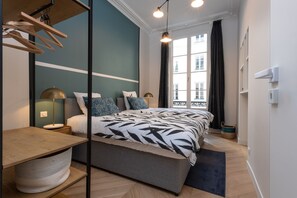 A modern bedroom with a bed, bedside tables, a lamp, and a window with curtains. - Sumptuous 3 Bedrooms Opéra - Grands Boulevards (Paris)