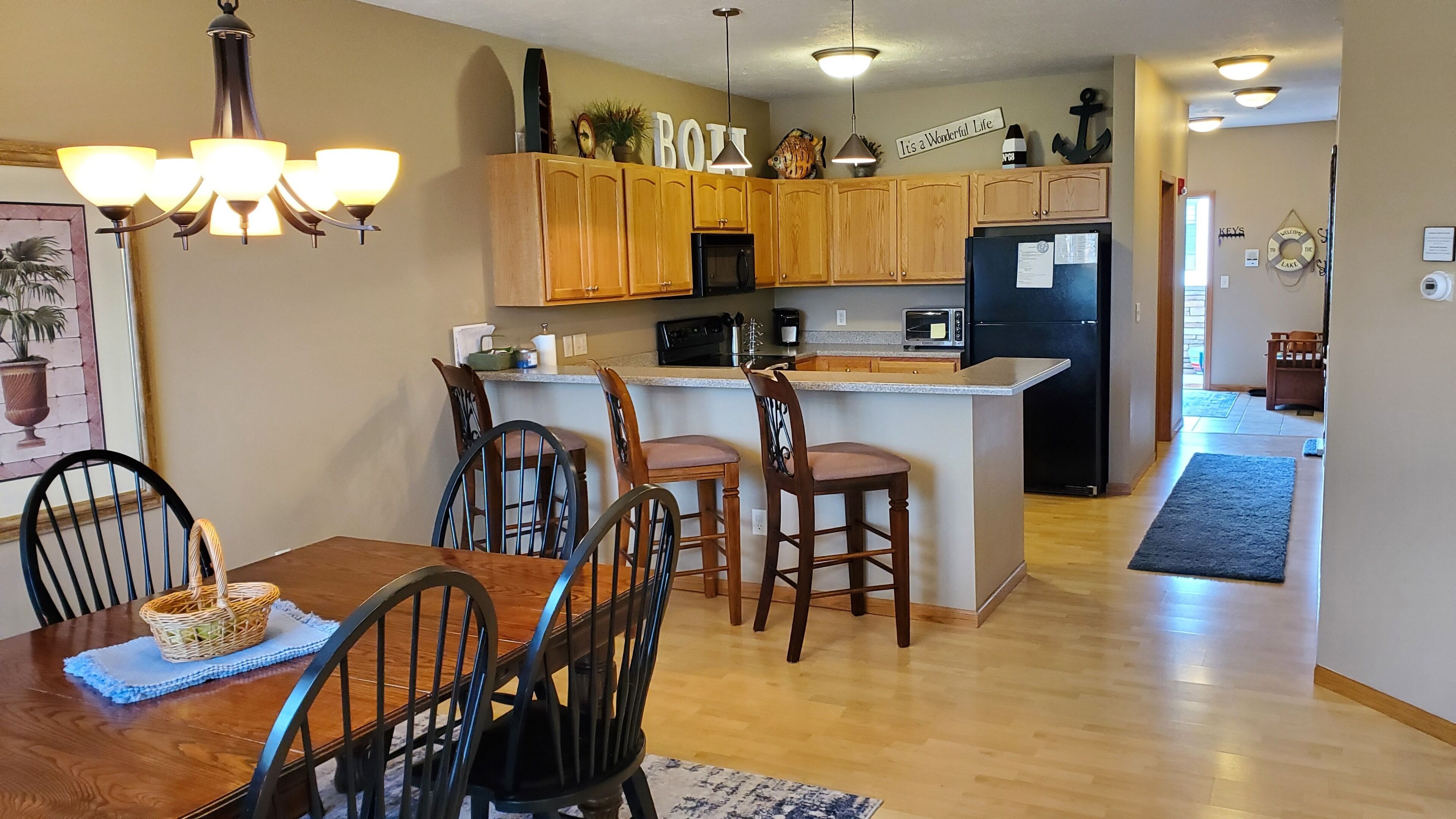 A kitchen with wooden cabinets, a black refrigerator, and a dining area with a wooden table and chairs.