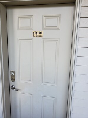 A white door with a sign reading 'D101 The Retreats' and a keypad lock.