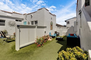 A white building with a sun decoration, a fenced yard, and outdoor furniture. - Blocks from the beach, enjoy this newly renovated studio. (Hermosa Beach)