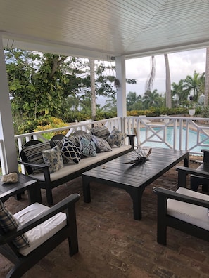 A covered outdoor seating area with a pool in the background. - Captivating 3-bed Villa in Montego Bay (Montego Bay)