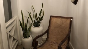 A corner room with a wooden chair, two potted plants, a hanging light fixture, and a wall-mounted sculpture. - Captivating 3-bed Villa in Montego Bay (Montego Bay)