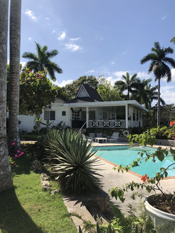 A white house with a pool, surrounded by palm trees and tropical plants. - Captivating 3-bed Villa in Montego Bay (Montego Bay)