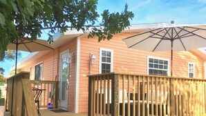 Une terrasse en bois avec une rambarde, un porche et un espace salon couvert avec un parasol.