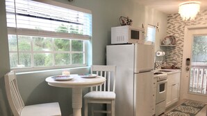 Une cuisine compacte avec un coin repas, comprenant un réfrigérateur blanc, une cuisinière et un four à micro-ondes.