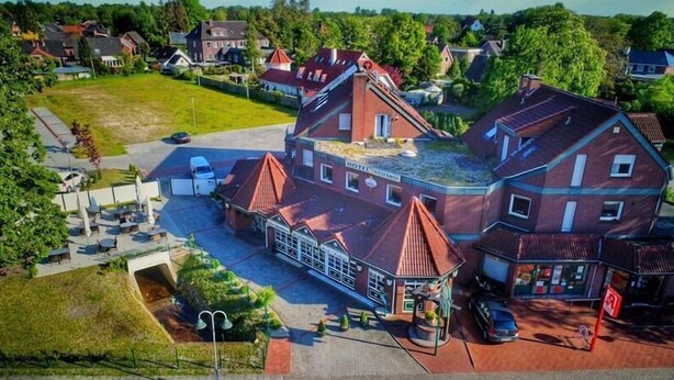 En stor, flereetagers bygning med et markant rødt tag, et overdækket udendørs opholdsområde og et skilt, der angiver, at det er et hotel.