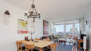 En moderne stue med spiseplads, store vinduer og udsigt over byen.