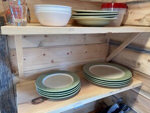 A wooden shelf with stacked plates and bowls. - A View for Two: Tiny House with BIG VIEWS (Fleetwood)