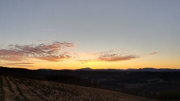 A landscape with a sunset over rolling hills and a clear sky.