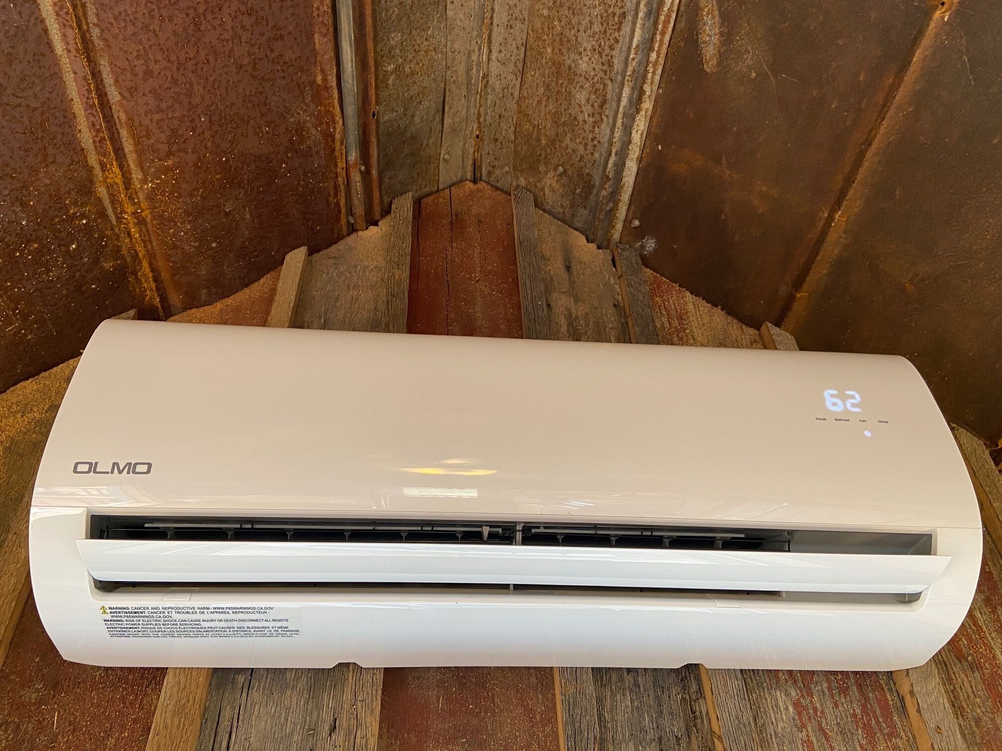 Eine weiße OLMO-Klimaanlage mit digitaler Anzeige, die eine Temperatur von 62 Grad zeigt.
