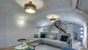 A cozy loft with exposed stone walls, a modern sofa set, and a spiral staircase. - Sweett | Trevise - Three Bedroom Apartment, Sleeps 6 (Paris)