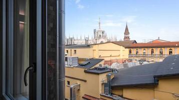 A view from a window overlooking a cityscape with historical buildings and a church spire.
