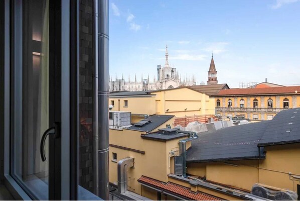 A view from a window overlooking a cityscape with historical buildings and a church spire.