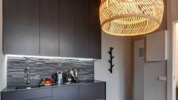 A modern kitchen with dark cabinets, a stone backsplash, and a fruit bowl on the counter.