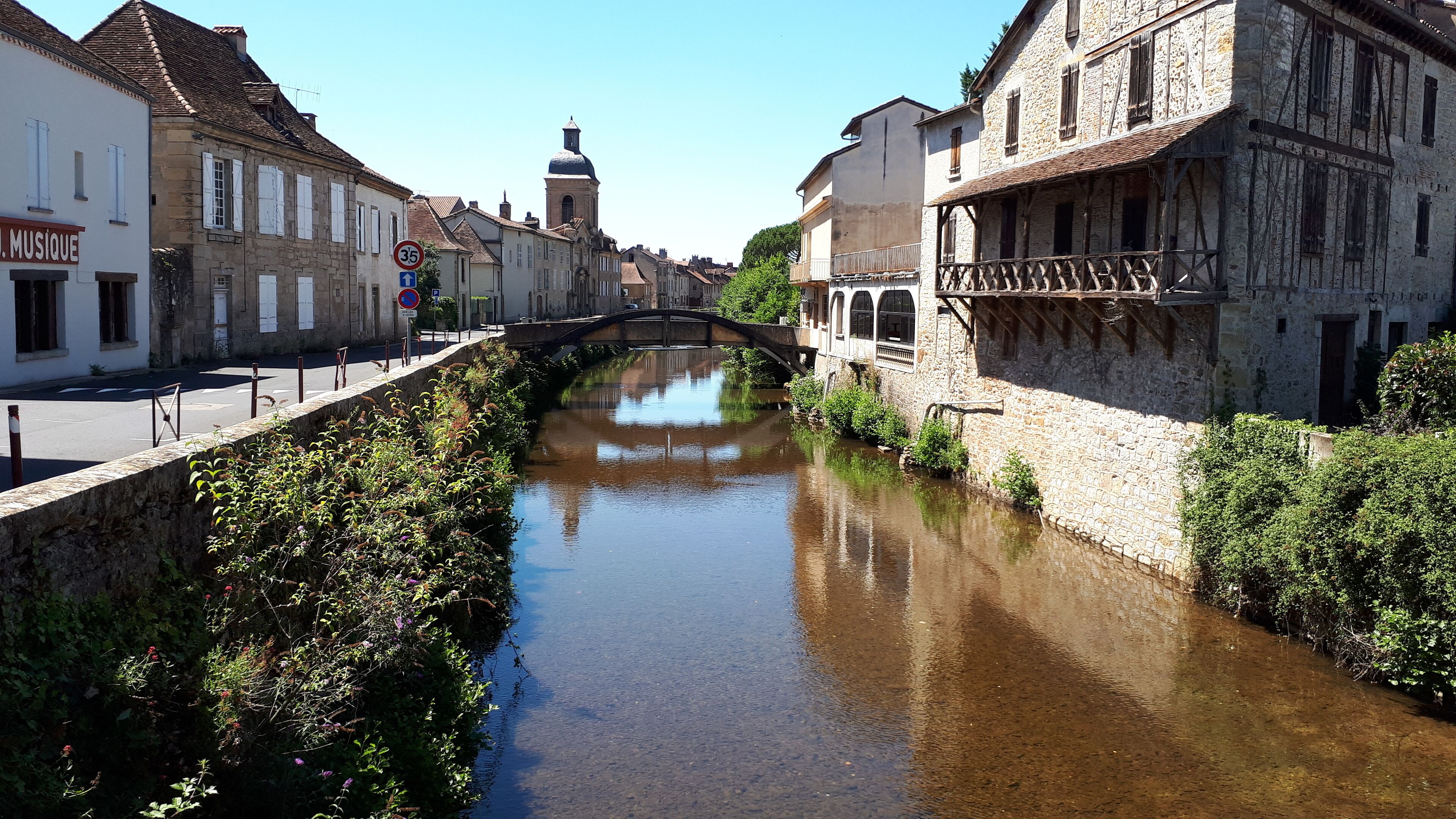 A narrow waterway flanked by stone buildings with a bridge crossing over.