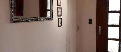 A hallway with a large mirror, a radiator, and a door with frosted glass panels.
