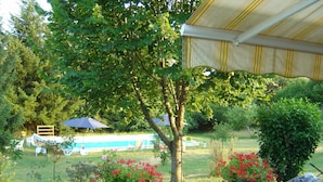 A garden with a pool, outdoor seating, and a covered area.